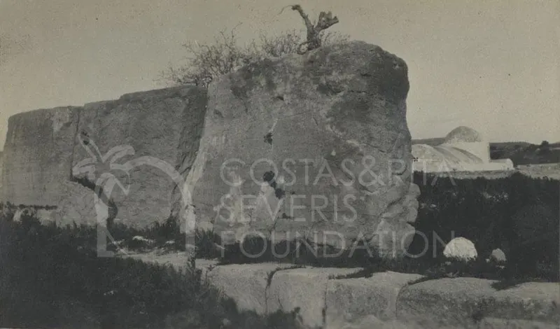 Large rough-hewn stone blocks of ruins at Palaepaphos with a whitewashed domed building behind