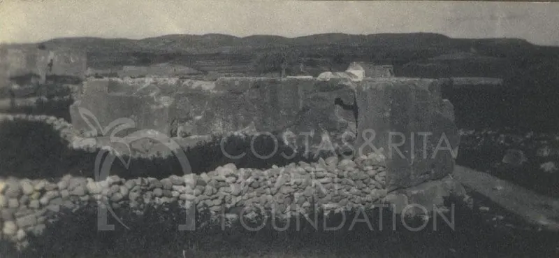 Large dressed stone blocks of ruins at Palaepaphos, with a dry-stone wall in the foreground and hills behind