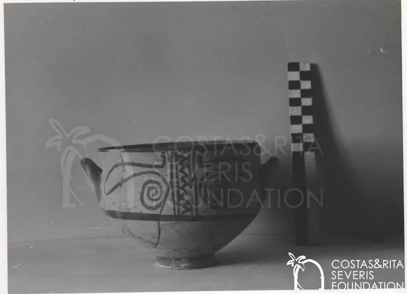 Footed pottery bowl with two side handles and dark painted spiral motifs, beside a chequered scale rod
