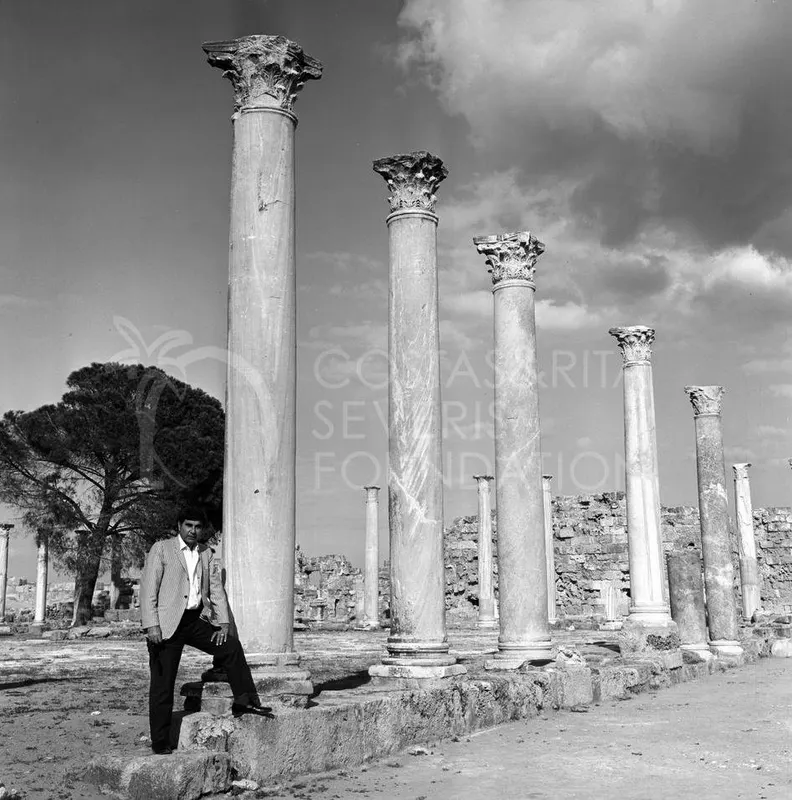 A man in a striped jacket stands beside tall columns with Corinthian capitals at Salamis.