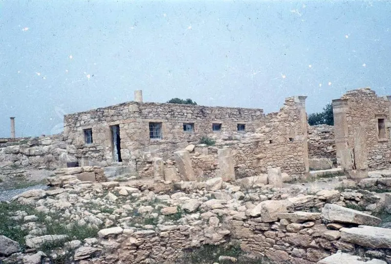 Stone ruins with a low building with small windows and fallen blocks in the foreground