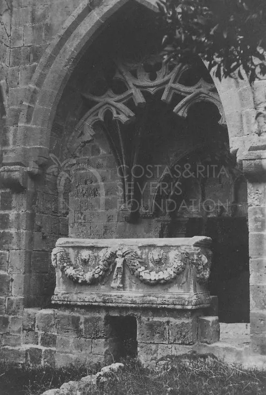 Carved stone sarcophagus with garland relief standing in a pointed arched niche of a ruined abbey