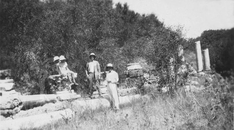 Four people in sun hats posing among fallen stone column drums and blocks at Salamis, with trees behind