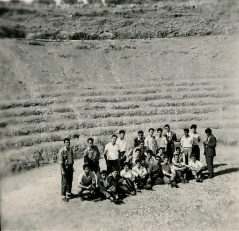 Group of young men posing on a gravel path in front of a stepped earth slope