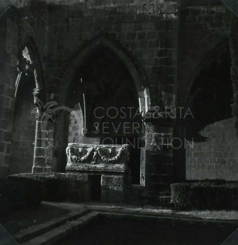 Stone sarcophagus with carved garlands in front of a pointed arch at Bellapais