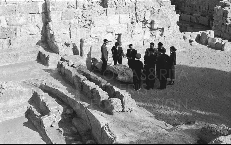 Group of people standing among ancient stone ruins at Salamis, with a large wrapped object on the ground