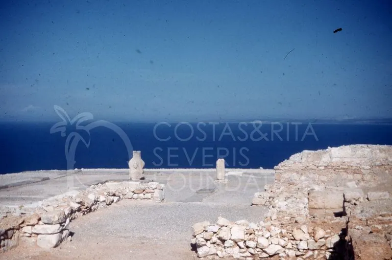 Ruined stone walls and two stone pillars on a headland overlooking the blue sea