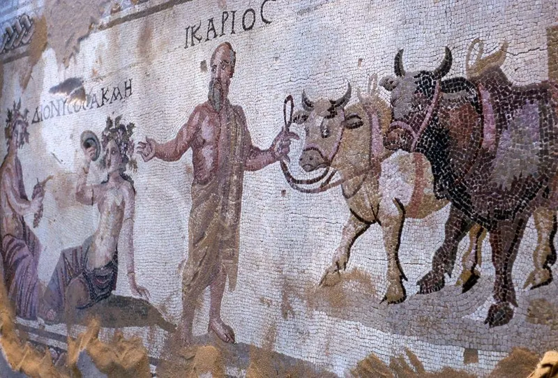 Mosaic of a bearded man leading oxen, with Greek lettering above him reading Ikarios