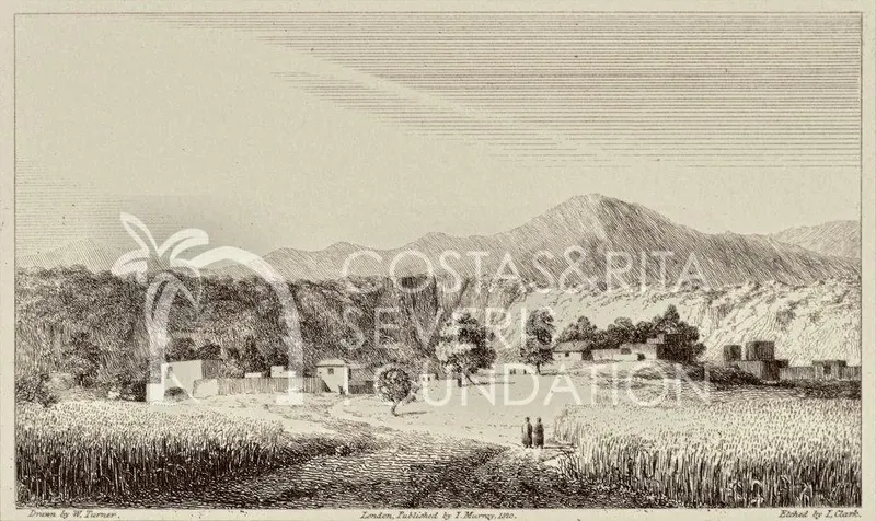 Distant village of flat-roofed houses and trees beneath hills, with two figures on a track through fields