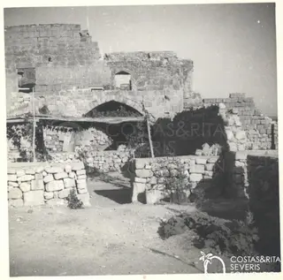 Ruined stone walls with a large arch and low rubble walls in the foreground at Kouklia