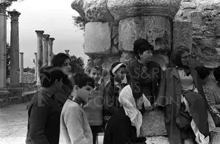 Group of people, including children, gathered beside a stone column with ruined columns behind them at Salamis