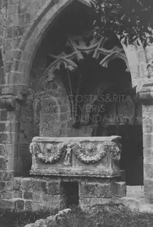 Carved stone sarcophagus with garland relief standing in a pointed arched niche of a ruined abbey