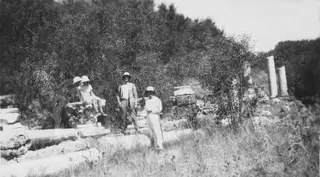 Four people in sun hats posing among fallen stone column drums and blocks at Salamis, with trees behind