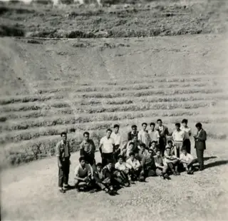 Group of young men posing on a gravel path in front of a stepped earth slope