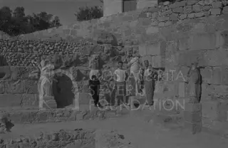 Three people pose among stone walls beside two draped marble statues at Salamis