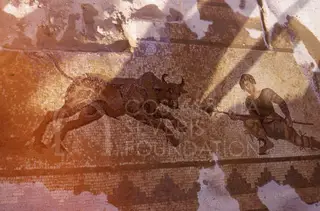 Floor mosaic of a spear-carrying hunter facing a charging bull