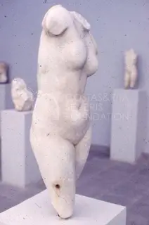Headless white marble female torso on a white pedestal in a museum gallery