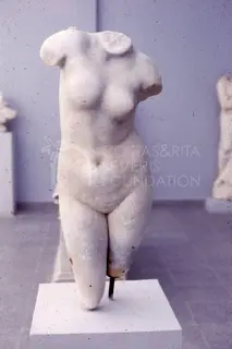Headless marble female torso on a white pedestal in a museum gallery