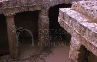 Rock-cut pillars and a stepped ledge inside a tomb chamber at the Tombs of the Kings, Paphos