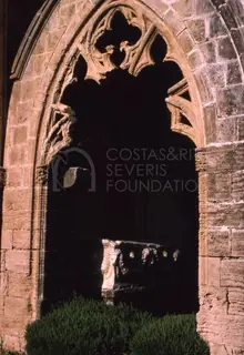 Carved stone sarcophagus in a shadowed recess beneath a pointed arch with tracery, Bellapais