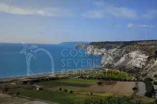 Sea bay with a sandy beach below white cliffs, with cultivated fields in the foreground