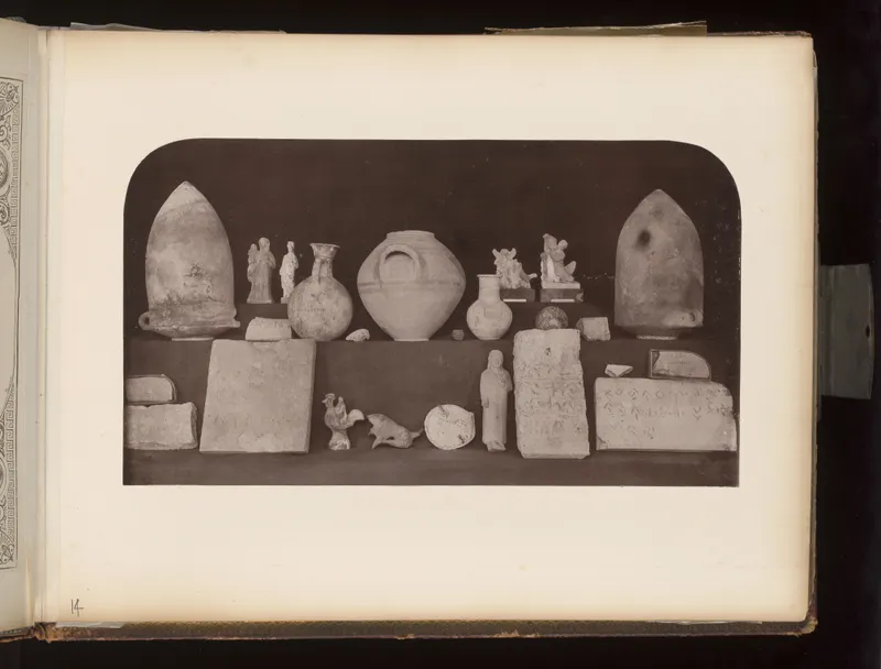 Two-tier display of pottery jars, jugs, small figurines, inscribed stone slabs and a rooster figure on a dark ground.