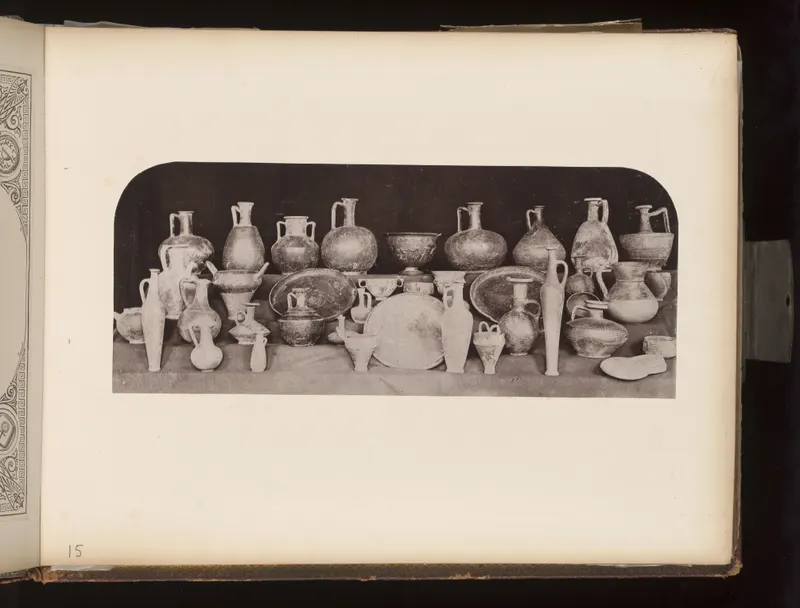 Rows of pottery jugs, jars, bowls and plates set out on a draped shelf against a dark background.