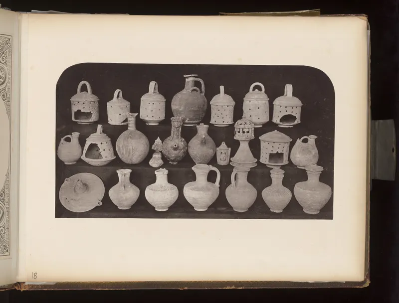 Three rows of pale clay vessels, lamps and small figures on a dark ground, mounted on an album page