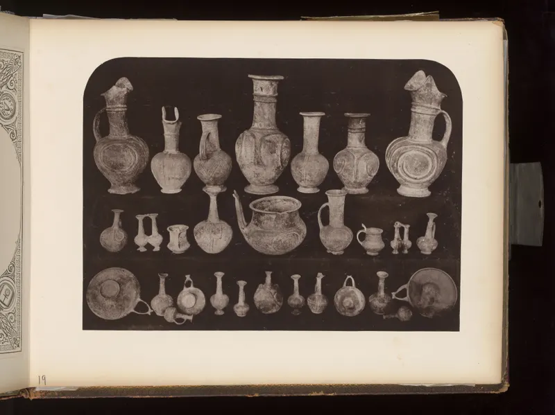 Three rows of pottery vessels on a dark ground: jugs, juglets, a bowl with a spout, and shallow dishes.