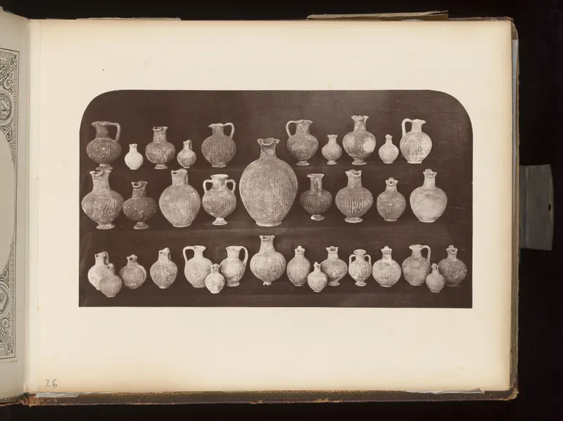 Three rows of pottery jugs, juglets and a large central jar on a dark background, mounted on an album page.