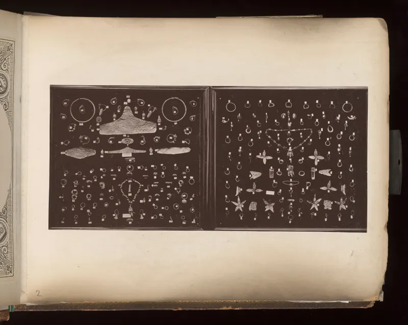 Two dark boards covered with rows of rings, earrings, pendants and beads, with small white tags beside many pieces