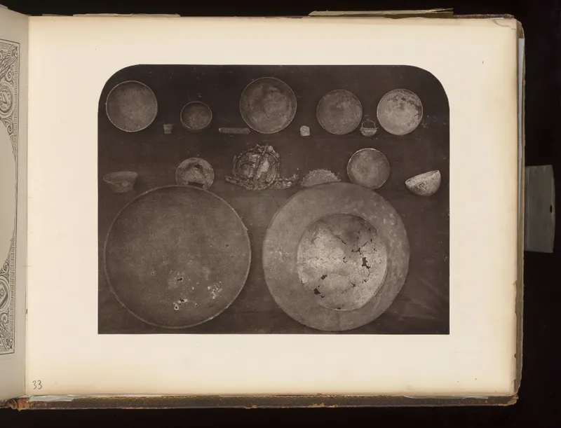 Shallow bowls, large dishes, a small handled vessel and a tangled cluster of jewellery laid out on a dark surface