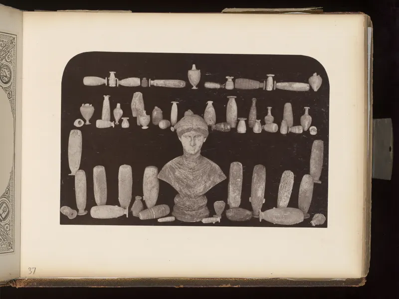 Many small vessels, cylindrical objects and a bust arranged in rows on a dark background