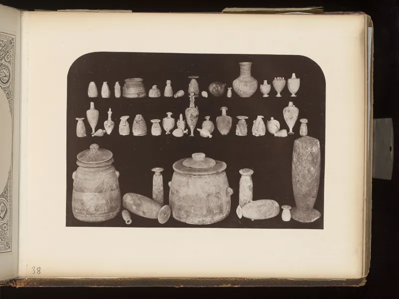 Rows of small vessels and juglets with two large lidded jars and a tall narrow vessel on a dark ground