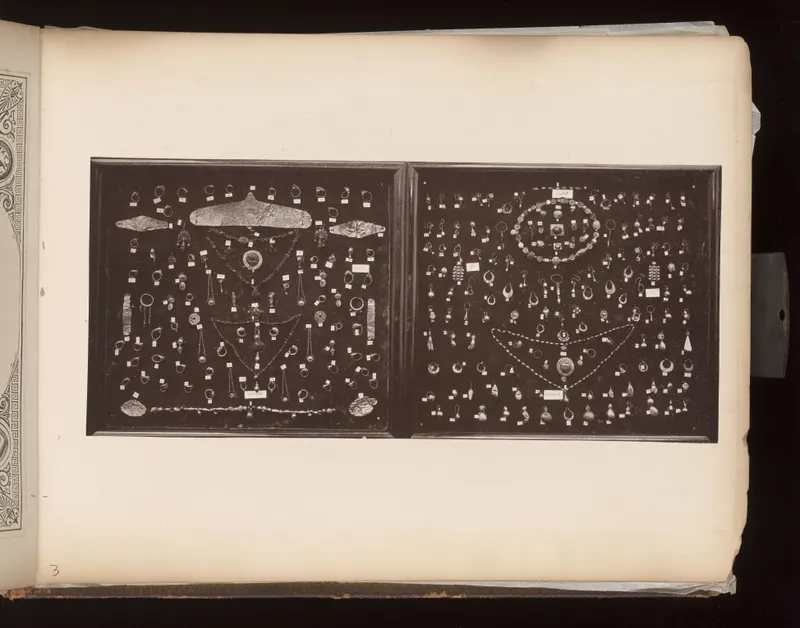 Two dark boards covered with gold jewellery: necklaces, chains, earrings, rings and pendants, each labelled with a small card.