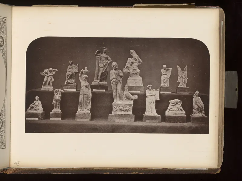 Terracotta figurines of human and animal figures standing and seated on small wooden bases, arranged on two tiers.