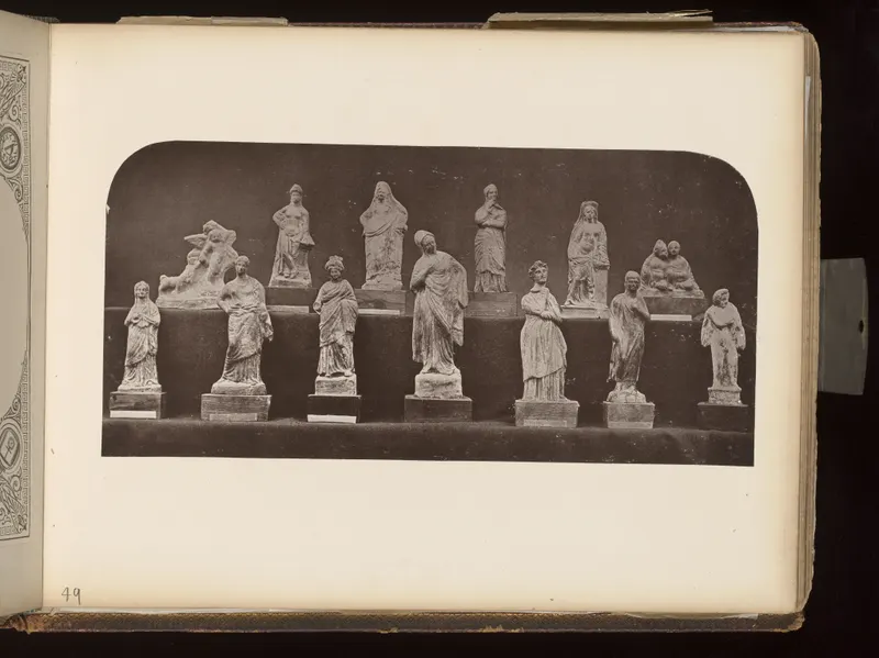 Two rows of about a dozen small figurines on bases against a dark background, mostly standing draped figures