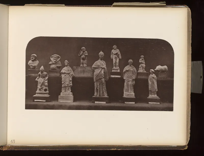 Row of about a dozen small figurines and one animal figure on wooden bases against a dark background