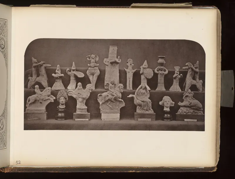 Two rows of small pale terracotta figurines of horses, riders, birds and figures arranged on shelves against a dark background.