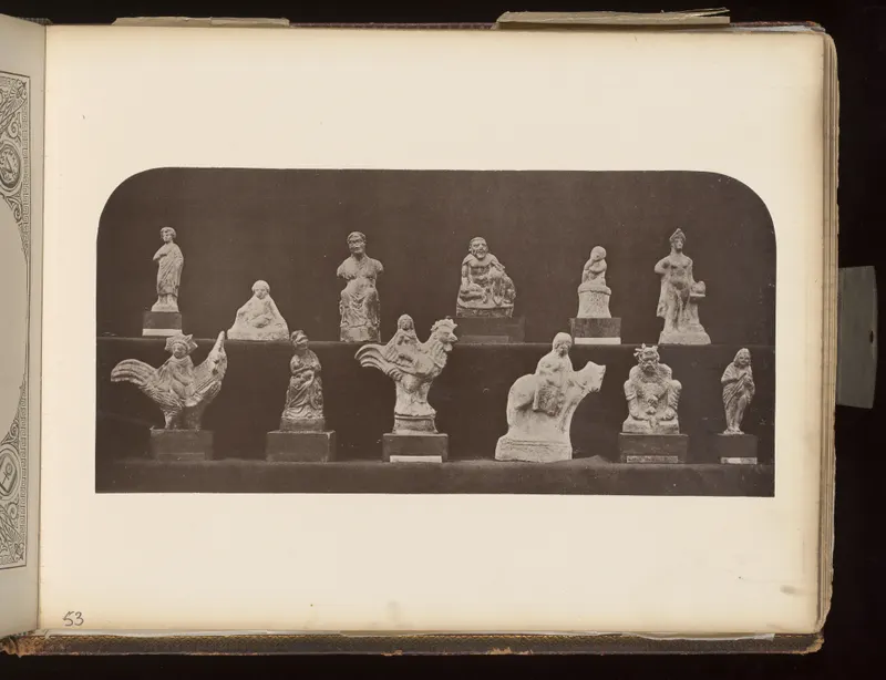 About a dozen small pale figurines of people and animals arranged in two rows against a dark backdrop