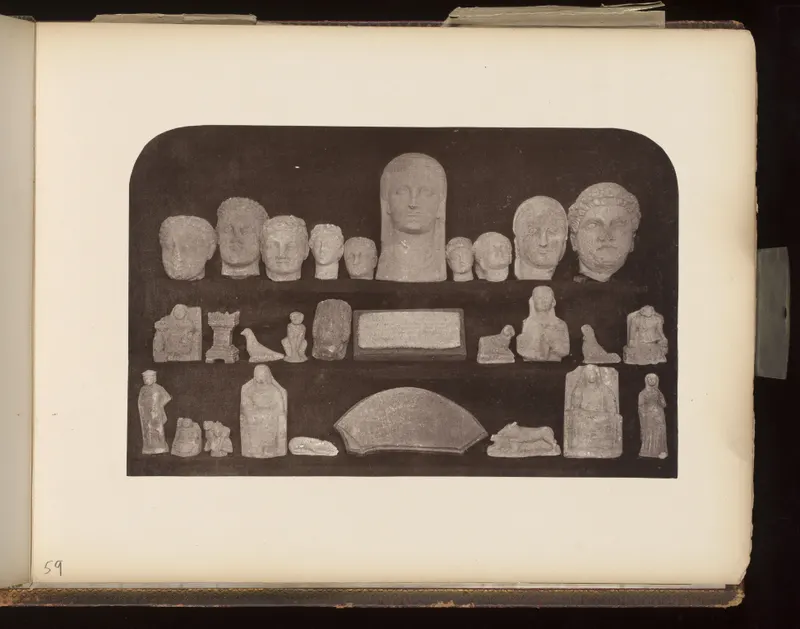 Stone heads in a top row, with small figures, reliefs and a fan-shaped slab in rows below, on a dark board.