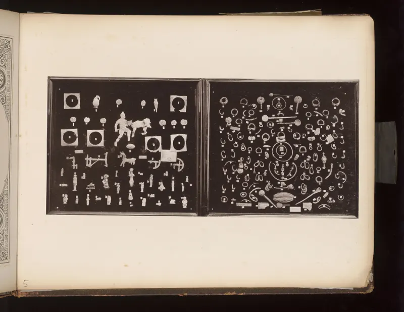 Two dark boards with small figurines, vessels and animal figures on the left and rings, bangles and rods on the right