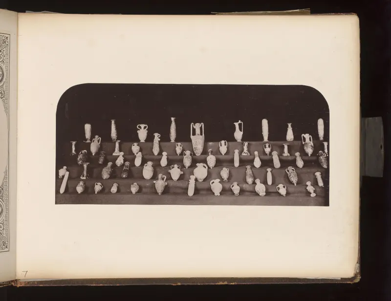 Many small jugs, juglets and bottles arranged in rows on four tiers of dark shelves