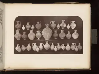 Pottery jugs, juglets and a large jar in rows