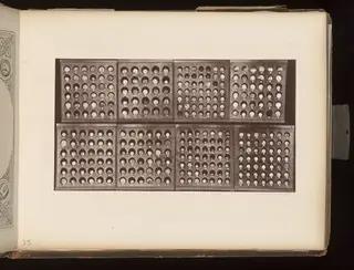Eight wooden trays in two rows, each holding rows of small round objects in circular recesses