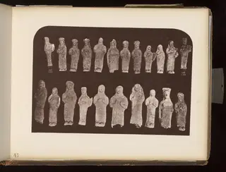 Two rows of about twenty small standing figurines laid out on a dark background
