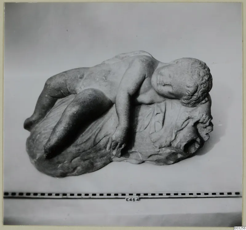 Marble sculpture of a reclining child with eyes closed, head resting on a draped base