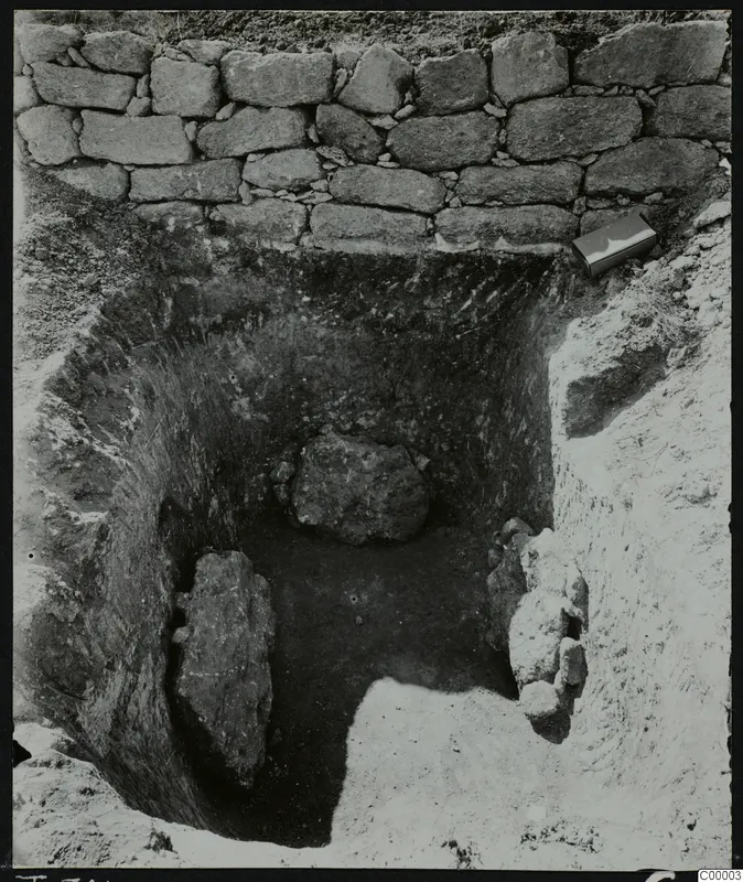 Excavated tomb at Lapithos, Vrysi tou Barba, with a dry-stone wall at the back and large stones inside the cut