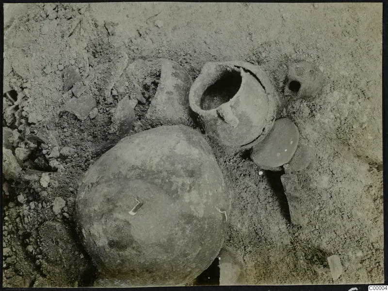 Pottery vessels and sherds lying in sandy soil during excavation of Tomb 302 at Lapithos