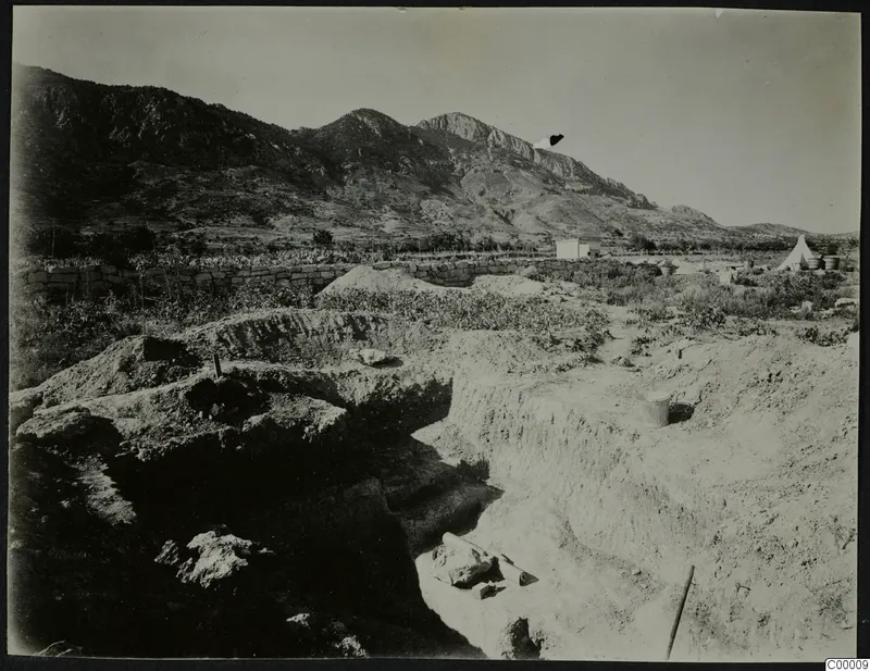 Excavation trenches at Lapithos with a white tent and a mountain ridge behind